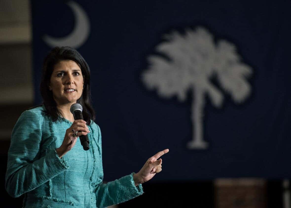 Image of Nikki Haley speaking into a microphone with the South Carolina state flag in the background