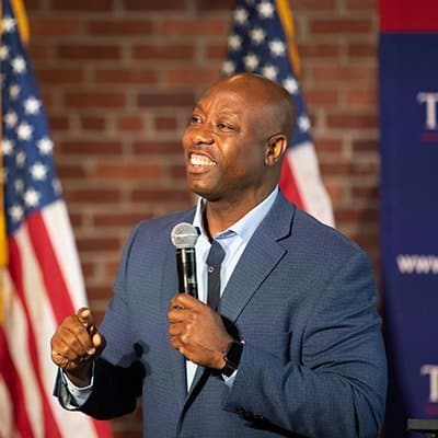Tim Scott smiling while speaking into a microphone.